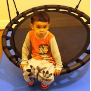 Toddler sitting on the 100cm black round nest swing indoors