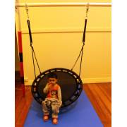 Toddler on the 100cm black nest swing hung from a padded stand indoors