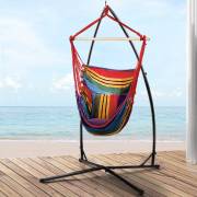 Rainbow hammock chair on the X stand on a deck by the sea