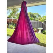 Pink purple tritone wrap swing hanging on a patio with a garden behind