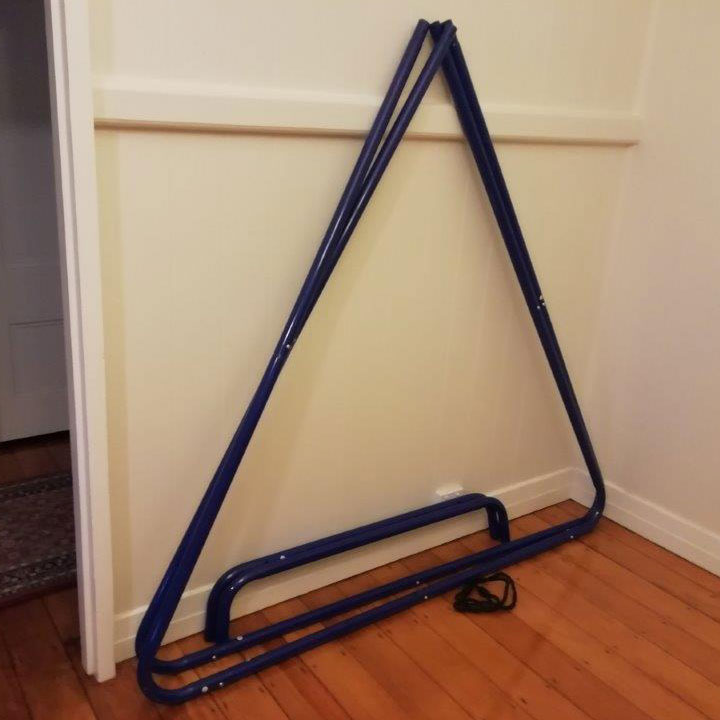 Medium swing set stand partly disassembled and leaning against a wall